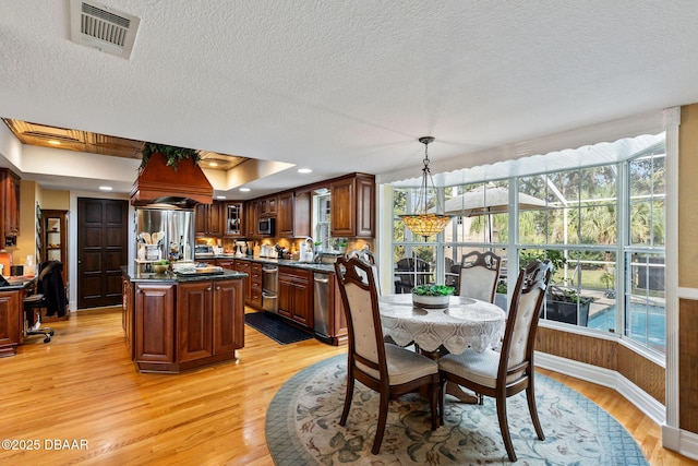 dining space featuring a textured ceiling, plenty of natural light, light wood-type flooring, and sink