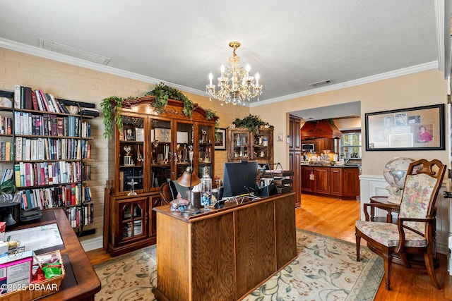 home office featuring light hardwood / wood-style flooring, brick wall, a notable chandelier, and ornamental molding