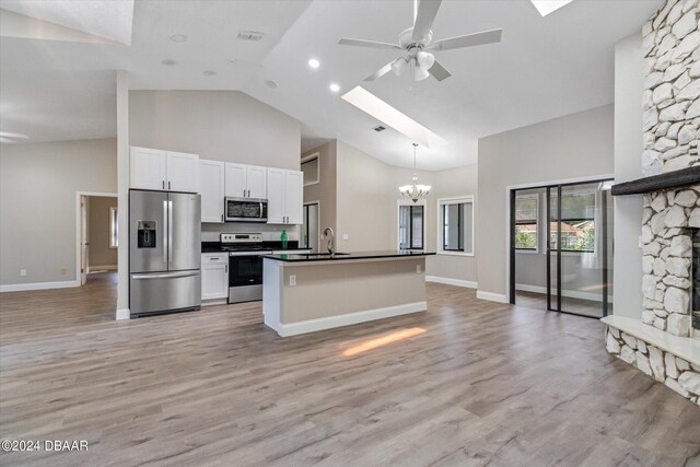 kitchen with light wood-type flooring, white cabinetry, a skylight, and appliances with stainless steel finishes