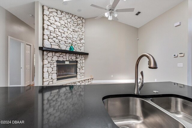 kitchen with a stone fireplace, lofted ceiling, sink, and ceiling fan