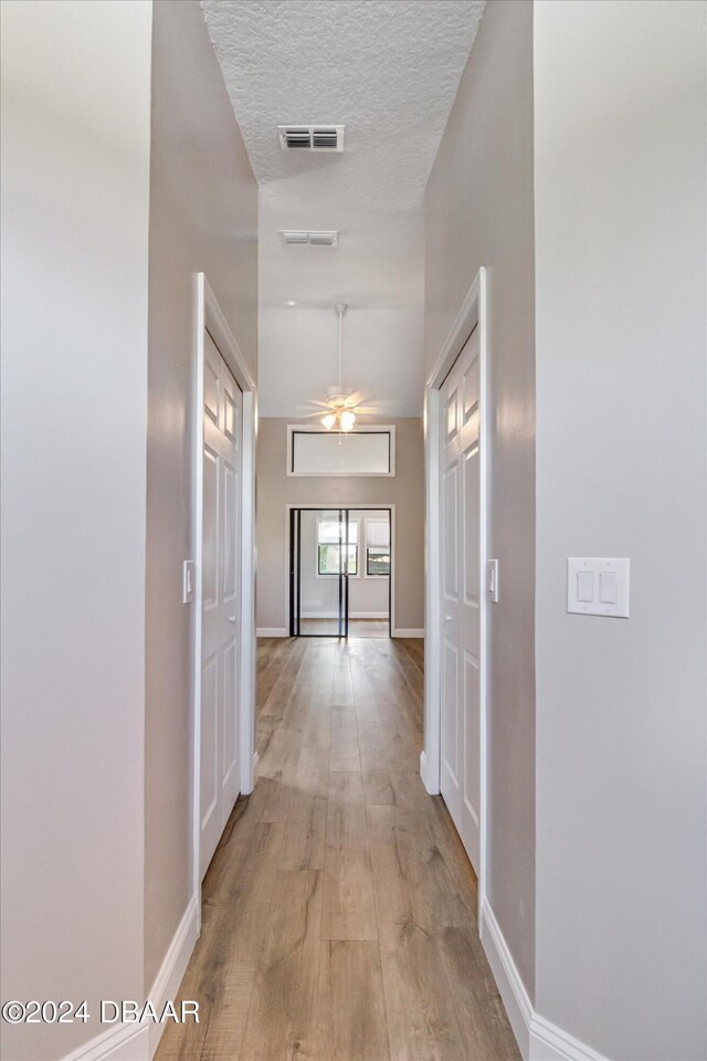 hallway featuring a textured ceiling and light hardwood / wood-style floors