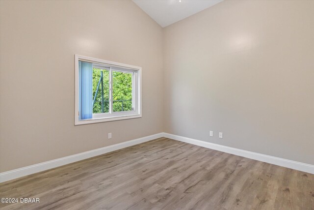 empty room featuring light wood-type flooring and high vaulted ceiling