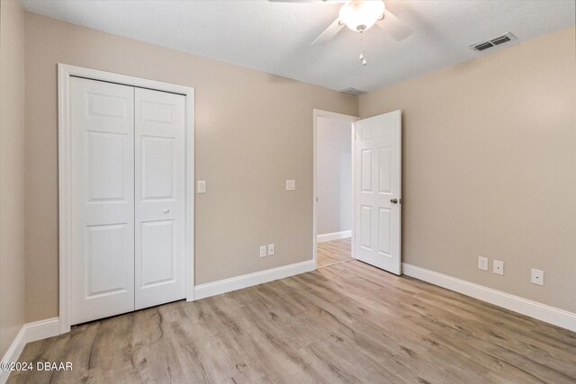 unfurnished bedroom featuring ceiling fan, a closet, and light wood-type flooring