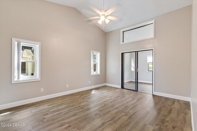 unfurnished bedroom with high vaulted ceiling, hardwood / wood-style flooring, ceiling fan, and a closet