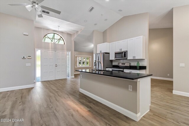 kitchen featuring stainless steel appliances, light hardwood / wood-style floors, white cabinetry, ceiling fan, and a kitchen island with sink