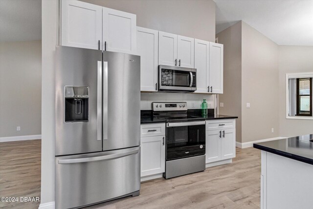 kitchen with white cabinets, lofted ceiling, light wood-type flooring, and appliances with stainless steel finishes