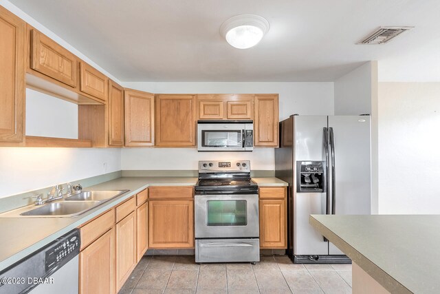 kitchen with stainless steel appliances, sink, and light tile patterned floors