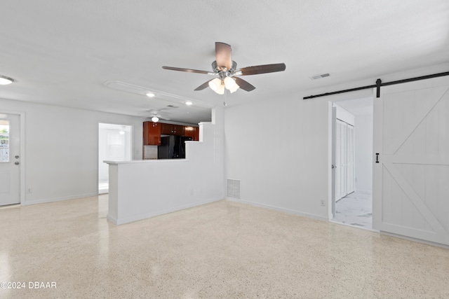 unfurnished living room featuring a barn door and a textured ceiling