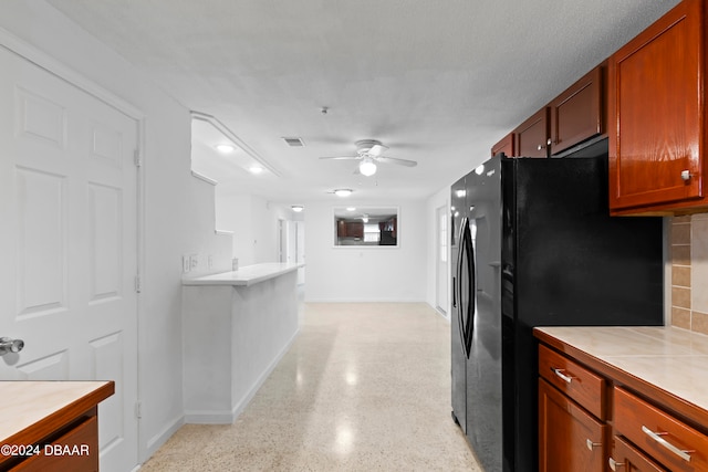 kitchen featuring ceiling fan, black refrigerator, a textured ceiling, and decorative backsplash