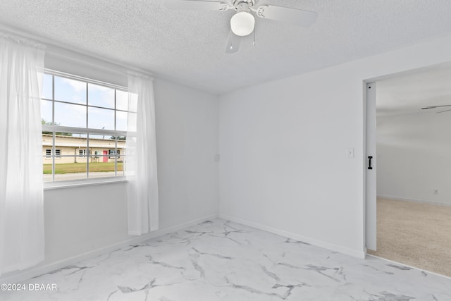 spare room with a textured ceiling, light carpet, and ceiling fan