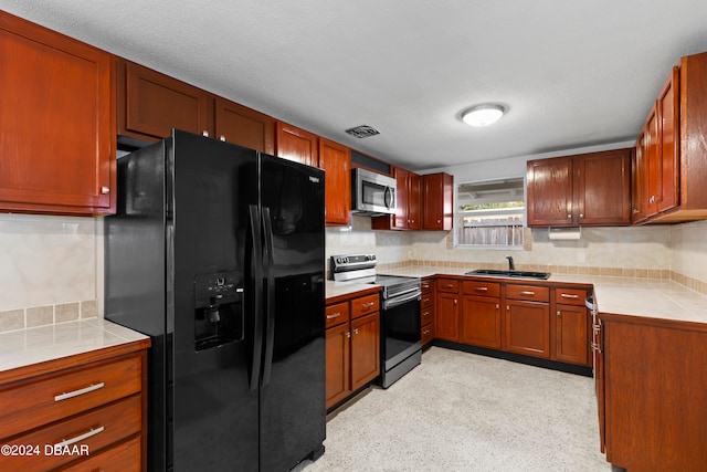 kitchen with stainless steel appliances, sink, a textured ceiling, backsplash, and tile counters