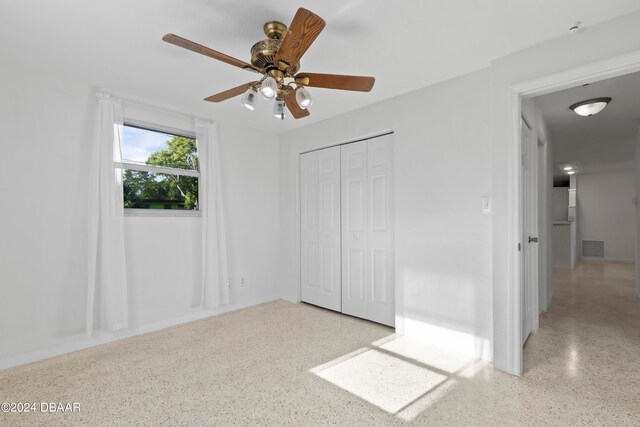 unfurnished bedroom with ceiling fan and a closet