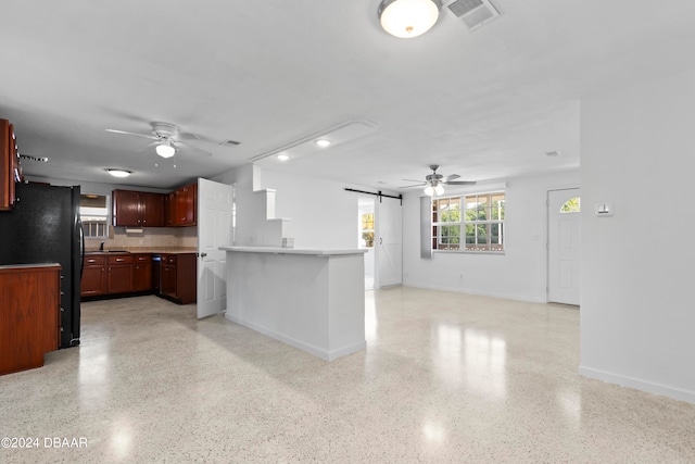 kitchen with kitchen peninsula, a barn door, ceiling fan, and black refrigerator