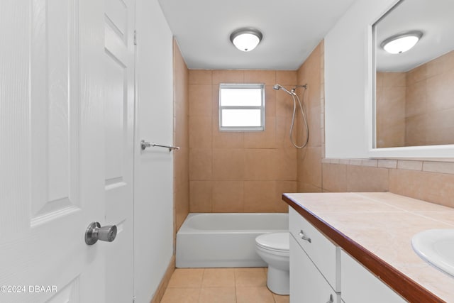 full bathroom featuring tile patterned flooring, vanity, tiled shower / bath combo, and toilet