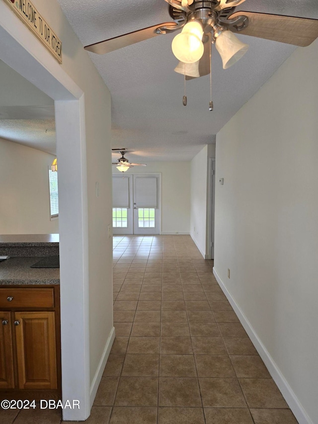 corridor with french doors, tile patterned floors, and a textured ceiling