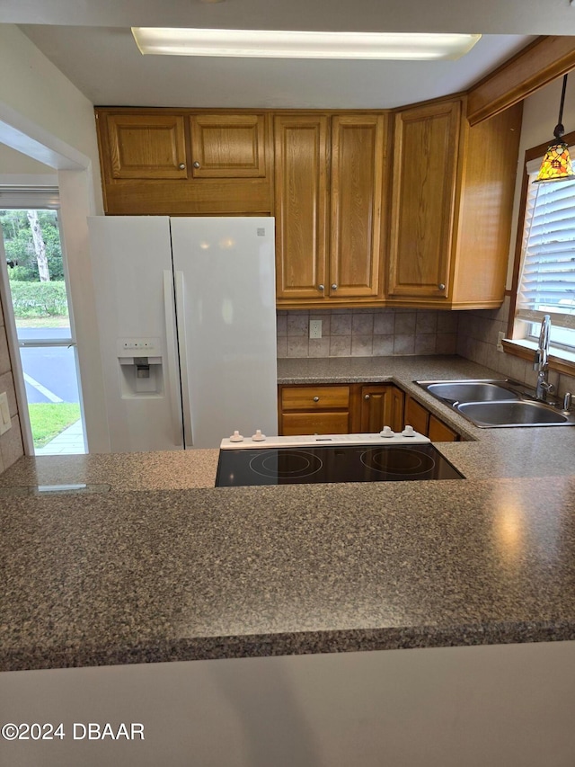 kitchen with black electric stovetop, sink, backsplash, and white refrigerator with ice dispenser