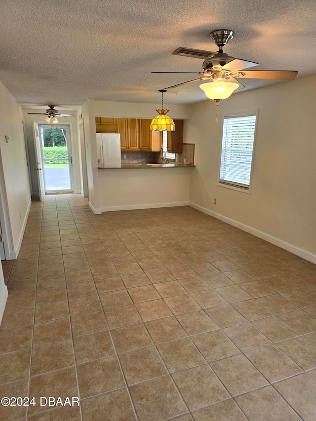 kitchen featuring kitchen peninsula, ceiling fan, a textured ceiling, light tile patterned floors, and white refrigerator