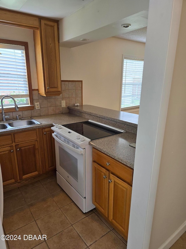 kitchen with tile patterned flooring, sink, backsplash, and white range with electric stovetop