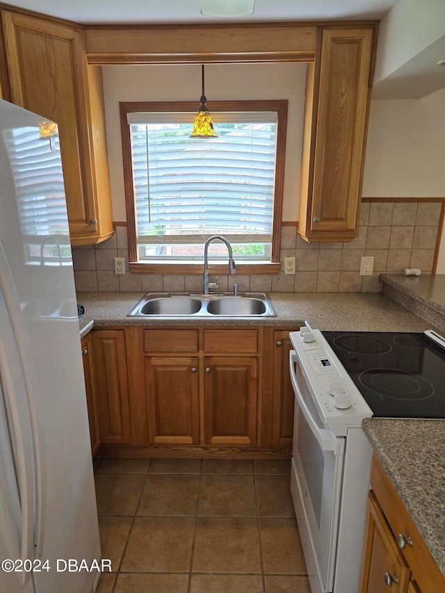 kitchen featuring hanging light fixtures, sink, dark tile patterned floors, backsplash, and white appliances