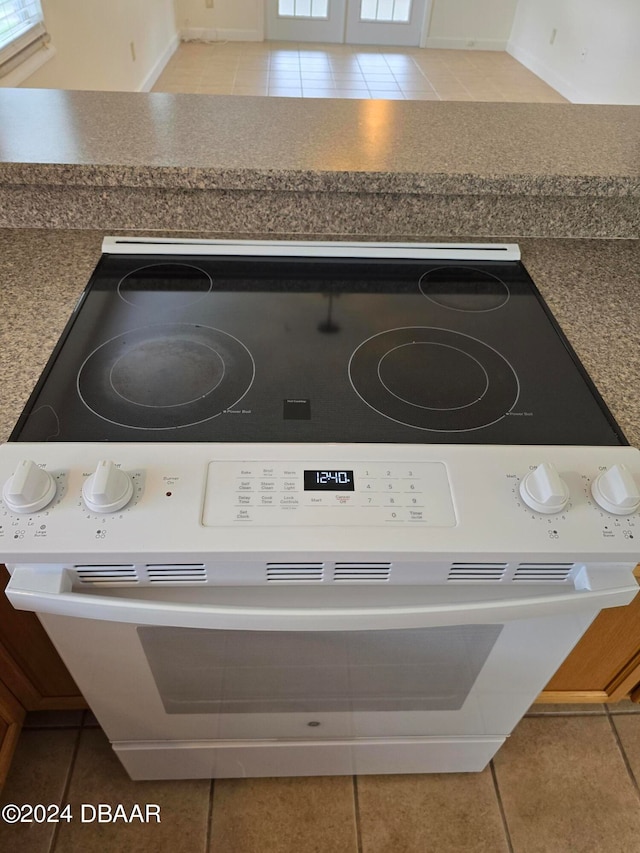 interior details featuring white range oven and tile patterned flooring