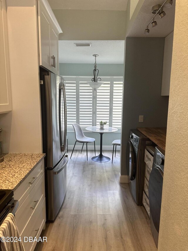 1021 Alabama Ave, Holly Hill, FL 32117 - kitchen featuring freestanding refrigerator, light wood-type flooring, range, white cabinets, and washer / clothes dryer