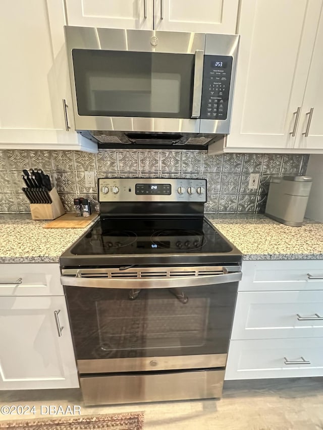 1021 Alabama Ave, Holly Hill, FL 32117 - kitchen with appliances with stainless steel finishes, backsplash, white cabinets, and light stone counters