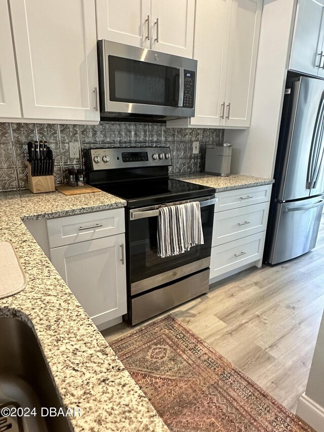1021 Alabama Ave, Holly Hill, FL 32117 - kitchen featuring appliances with stainless steel finishes, white cabinets, decorative backsplash, and light wood-style flooring