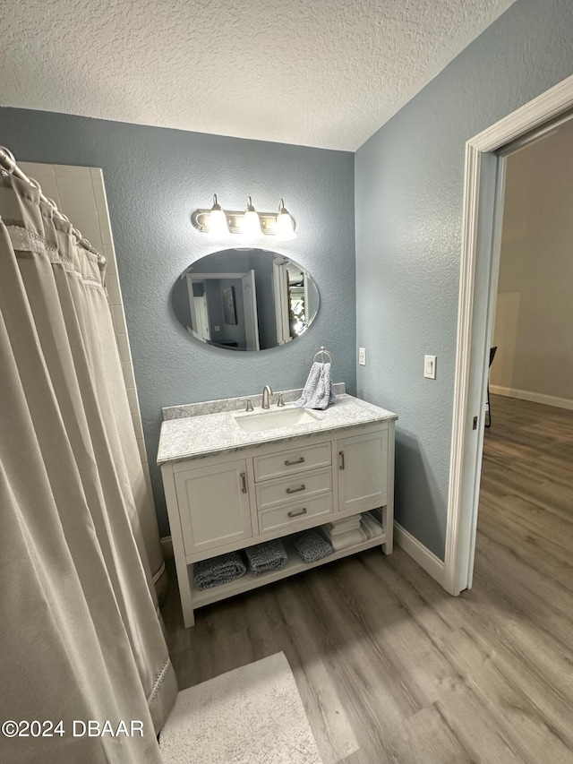 1021 Alabama Ave, Holly Hill, FL 32117 - bathroom with a textured wall, a textured ceiling, wood finished floors, vanity, and baseboards