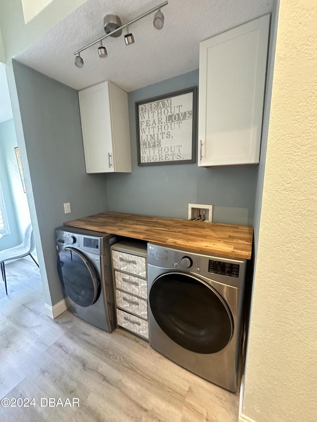 1021 Alabama Ave, Holly Hill, FL 32117 - washroom featuring washing machine and dryer, cabinet space, light wood finished floors, a textured ceiling, and baseboards