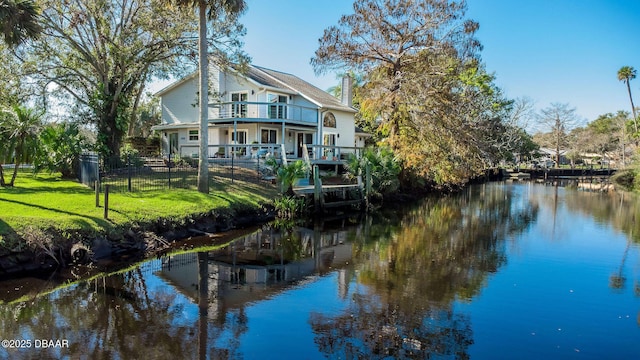 rear view of property with a lawn, a balcony, and a water view