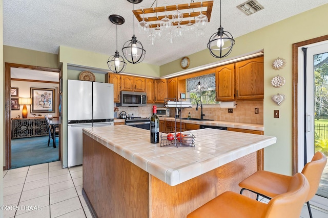 kitchen with tile countertops, a center island, stainless steel appliances, and tasteful backsplash