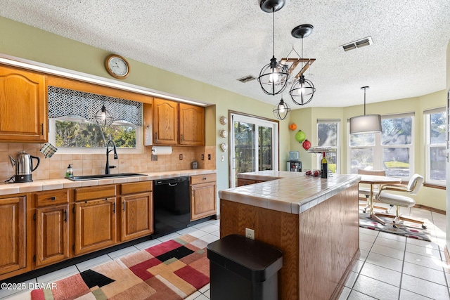 kitchen featuring sink, hanging light fixtures, black dishwasher, decorative backsplash, and a kitchen island