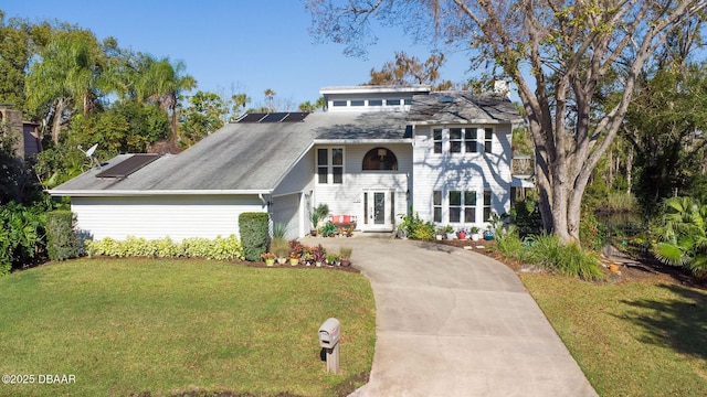 view of front of house with solar panels, a garage, a balcony, and a front yard