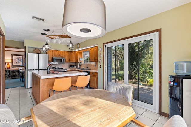 kitchen featuring sink, stainless steel appliances, a kitchen island, tasteful backsplash, and light tile patterned flooring