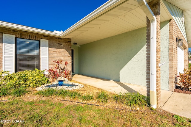 property entrance with stucco siding and brick siding