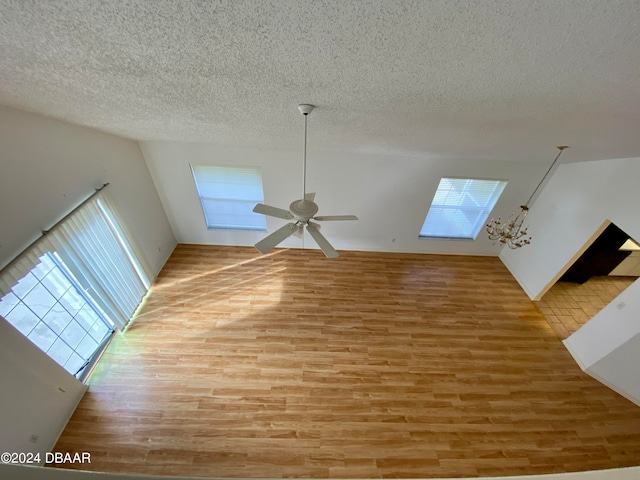 unfurnished living room with a textured ceiling, wood-type flooring, and ceiling fan