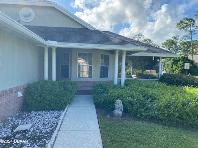 doorway to property featuring a porch and a lawn