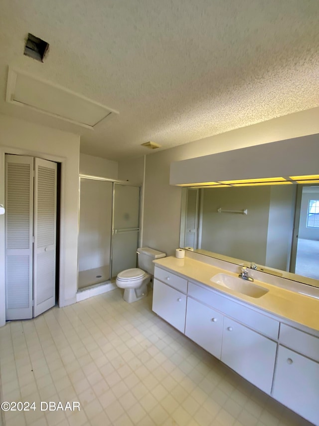 bathroom featuring toilet, vanity, a textured ceiling, and a shower with shower door