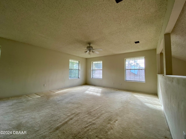 empty room with a textured ceiling, light carpet, and ceiling fan