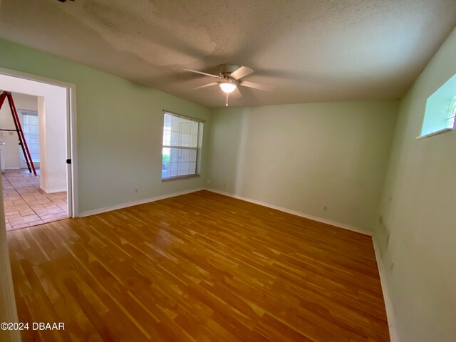 empty room with a textured ceiling, hardwood / wood-style flooring, and ceiling fan