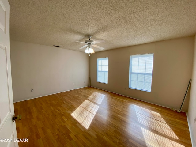 empty room with light hardwood / wood-style floors, ceiling fan, and a textured ceiling