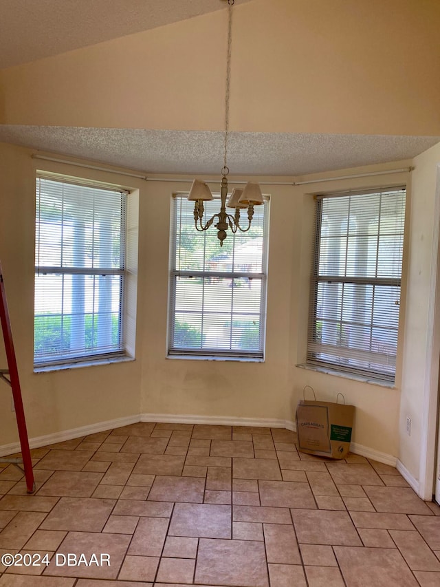 unfurnished dining area with light tile patterned flooring, a chandelier, a textured ceiling, and lofted ceiling