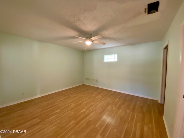 spare room with a textured ceiling, ceiling fan, and light hardwood / wood-style flooring