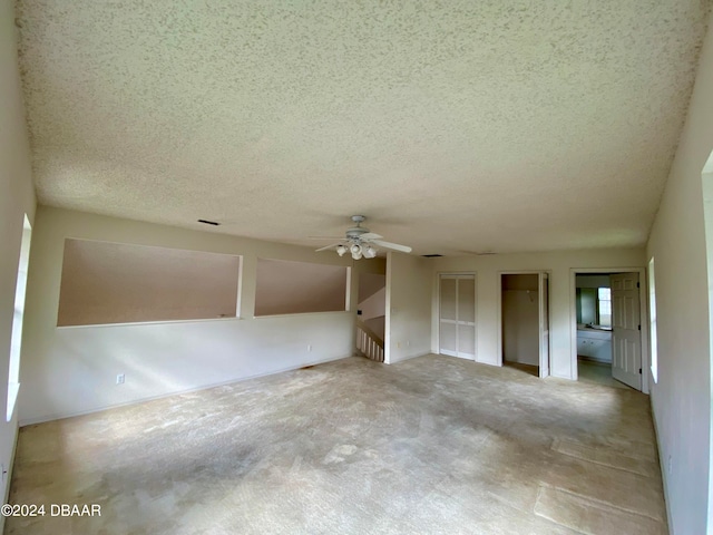 unfurnished room with ceiling fan, a textured ceiling, and light carpet