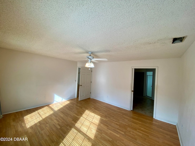 empty room featuring light hardwood / wood-style floors, a textured ceiling, and ceiling fan