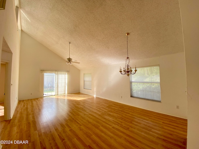 unfurnished living room featuring high vaulted ceiling, hardwood / wood-style floors, ceiling fan with notable chandelier, and a textured ceiling