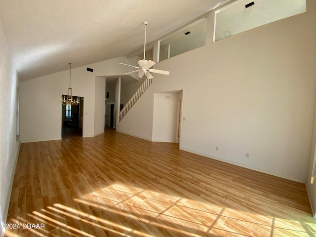 unfurnished living room featuring wood-type flooring, ceiling fan with notable chandelier, a textured ceiling, and high vaulted ceiling