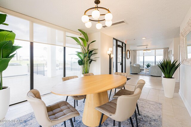 dining area featuring a textured ceiling, light tile patterned floors, a chandelier, and floor to ceiling windows