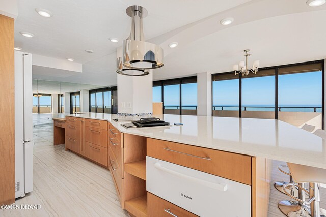 kitchen featuring a notable chandelier, a breakfast bar area, a water view, and decorative light fixtures