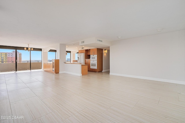 unfurnished living room with a wall of windows and a chandelier